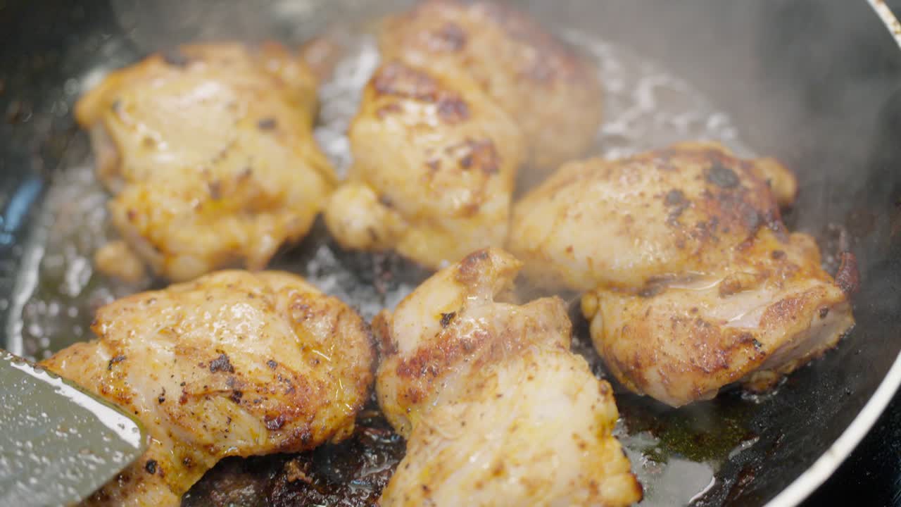 Primo piano di cosce di pollo marinate che cuociono a fuoco vivo in una padella con olio bollente e vapore