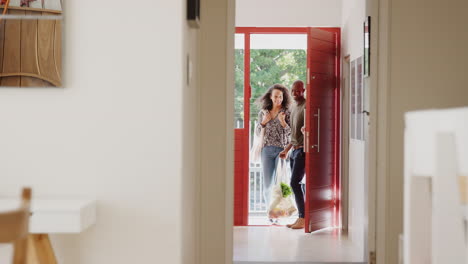 couple returning home from shopping trip carrying groceries in plastic free bags