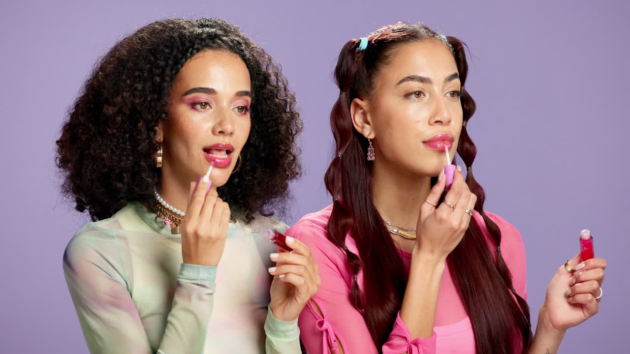 Two women applying lip gloss