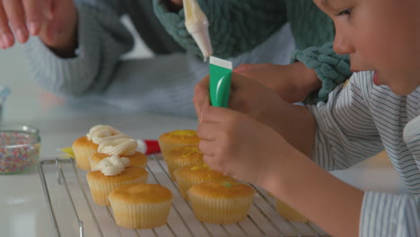 Cerca-De-La-Madre-Y-Los-Niños-En-La-Cocina-Decorando-Pastelitos-Juntos