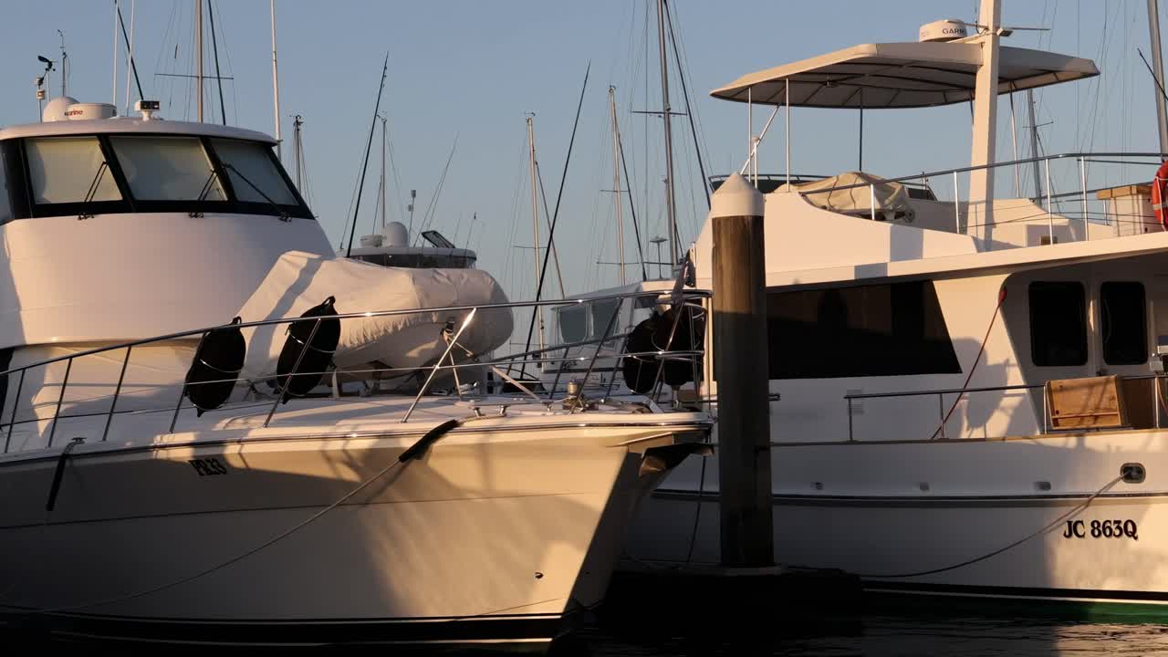 Close-up view of luxury yachts docked at a marina, captured during the golden evening light.