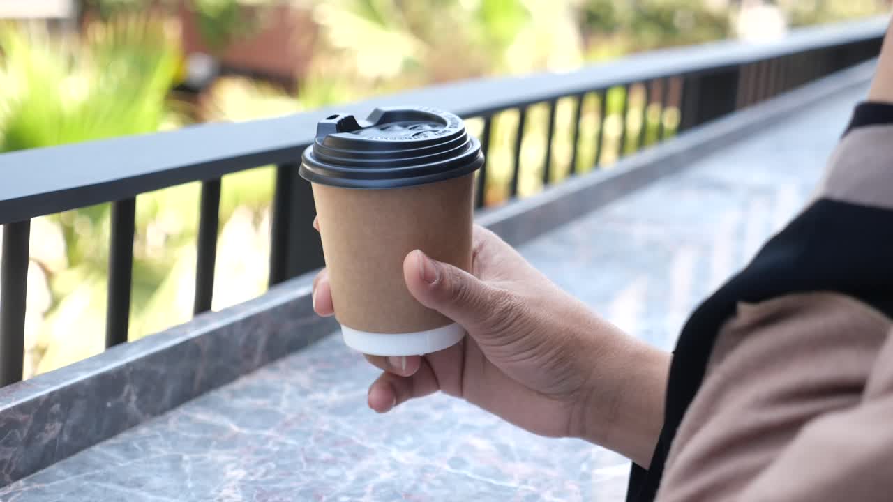 Hand holding a paper coffee cup outdoors
