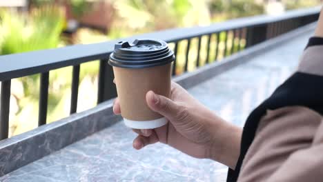 hand holding a paper coffee cup outdoors