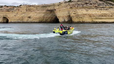 speed boat sailing in portugal coast, cliffs with sea caves in background