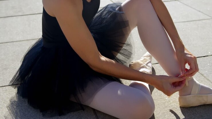 Female ballet dancer tying the ribbon on her ballet shoes 4k