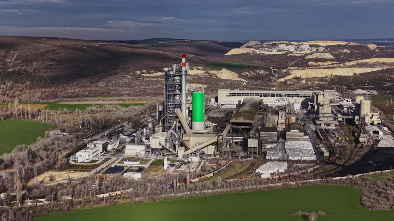Stabilimento industriale con torre verde in un paesaggio collinare