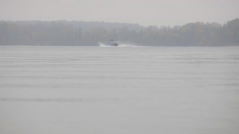 misty lake during autumn season with sailing motor boat