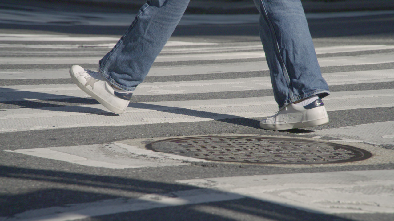 Slow motion shot of an unrecognizable pedestrian walking in Midtown Manhattan. Shot from the waist down focusing on the pedestrian’s legs.