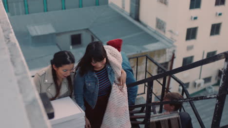 group of young multiracial friends walking up fire escape stairs ready for rooftop party chatting sharing excitement for weekend celebration