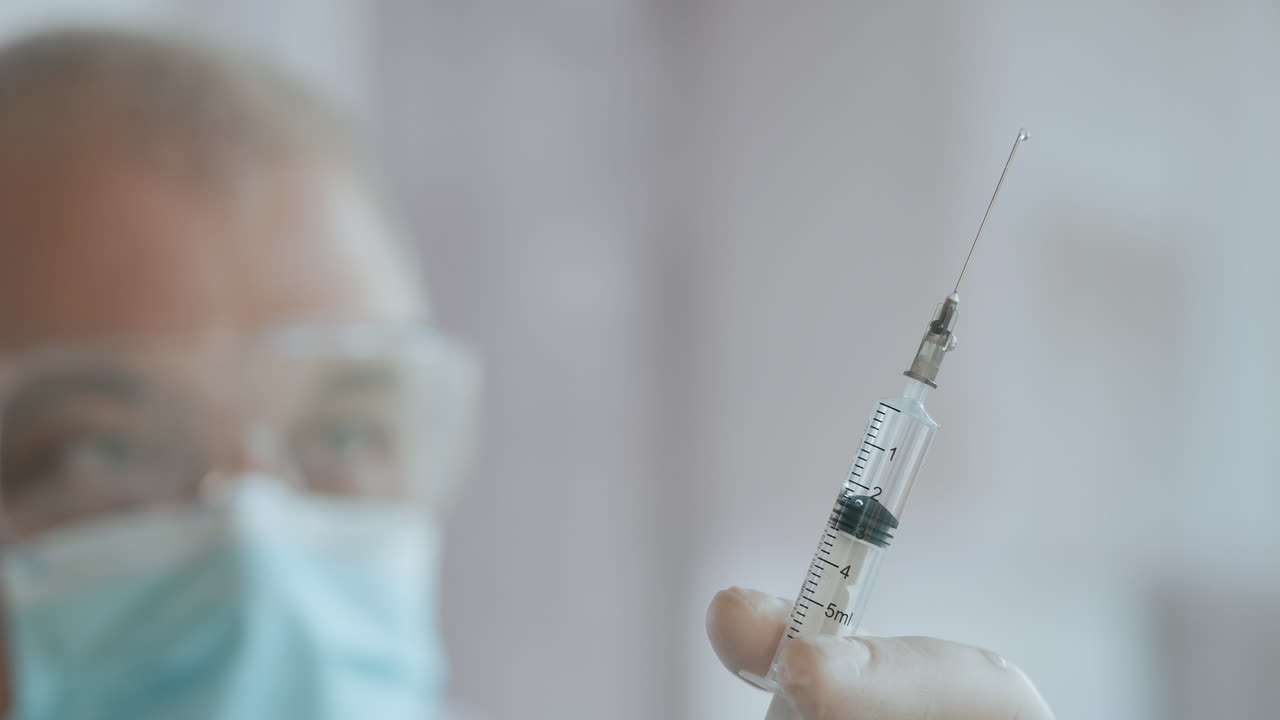Medic Hands Preparing a Syringe with Antibiotic for Intravenous Treatment. A syringe with a medicine with a vaccine is in the hands of a doctor the medicine is squeezed out of the syringe drops. High quality 4k footage