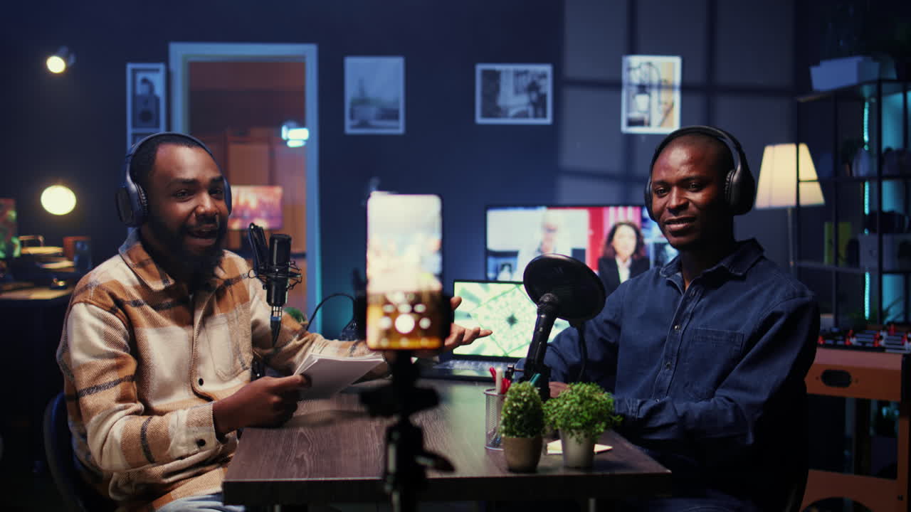 Man on podcast filming with cellphone on tripod while talking with guest during marathon stream