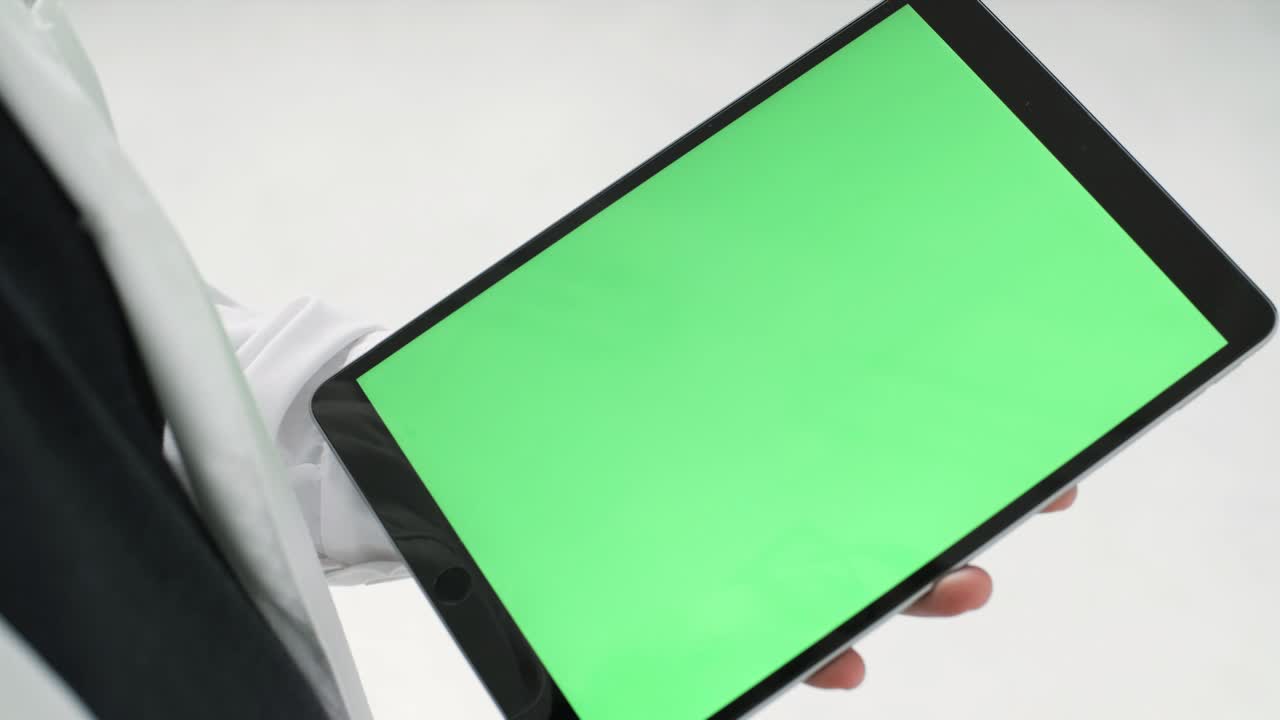 녹색 화면 을 가진 태블릿 을 들고 있는 사람