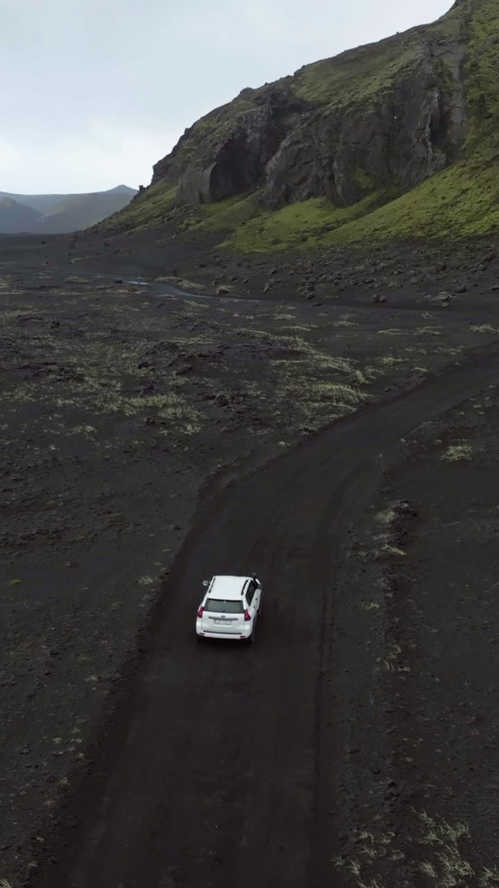 Vertical drone shot around a 4x4 truck driving in the muddy highlands of Iceland