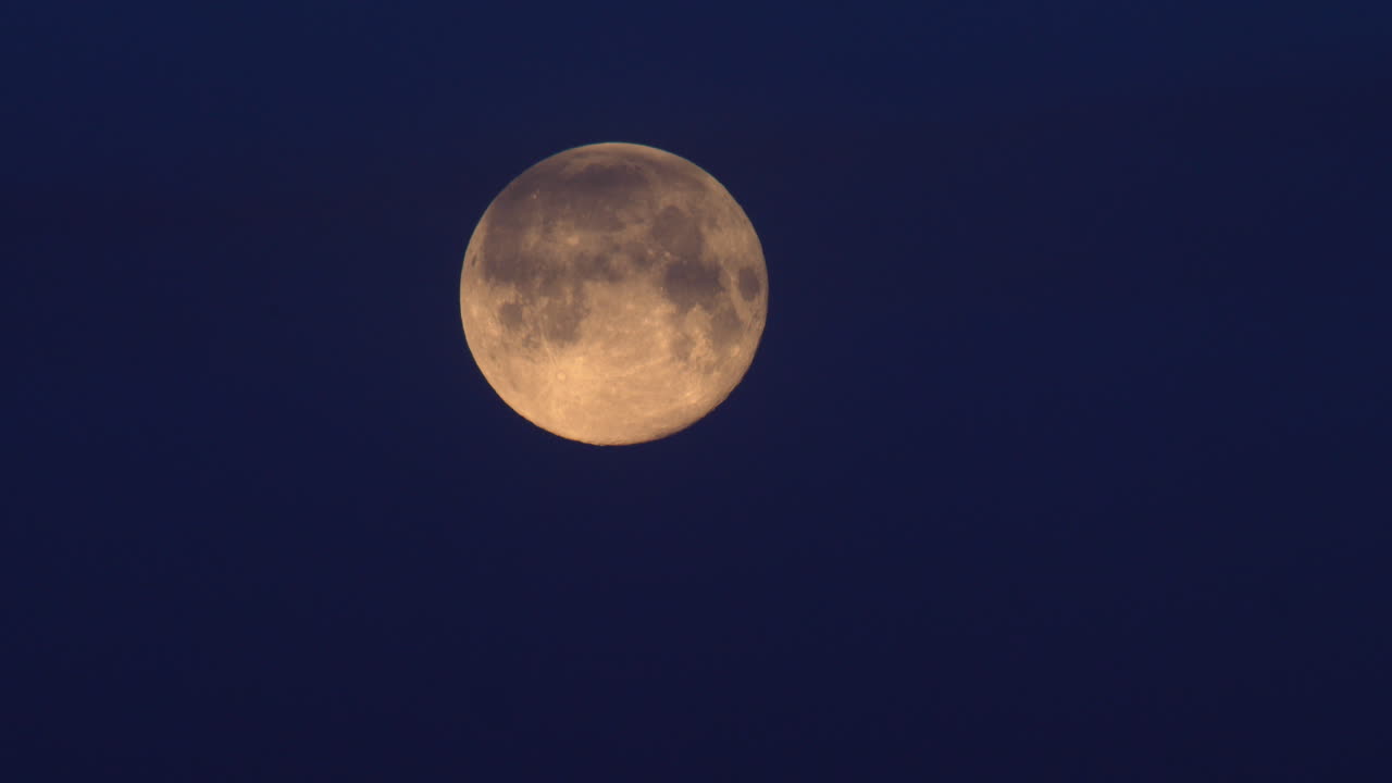 Lua Cheia brilhando com um fundo de céu noturno azul - Plano de ângulo baixo.