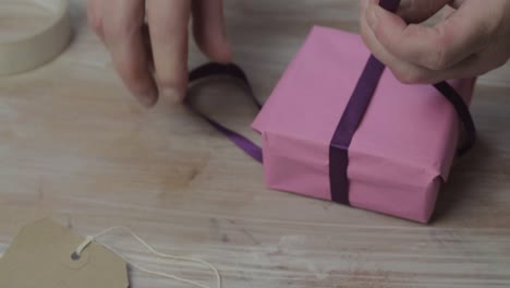Woman tying a ribbon bow on wrapped gift