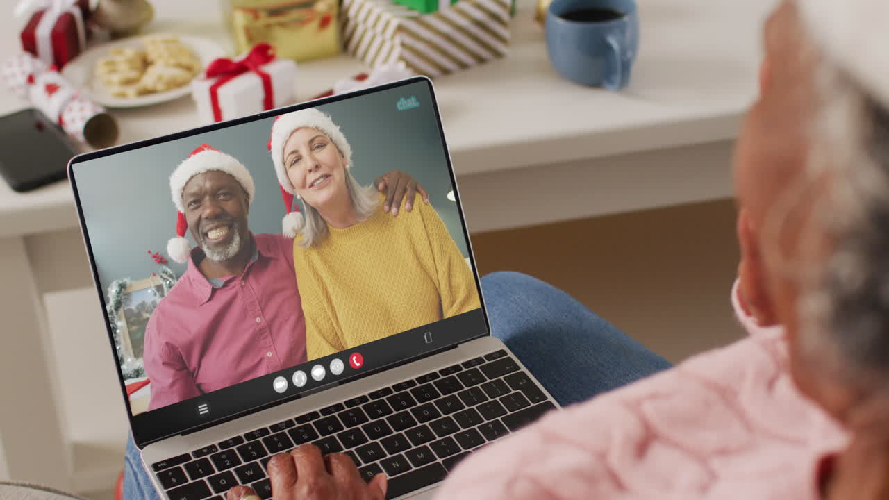 una mujer afroamericana de edad avanzada tiene una videoconferencia de navidad con una pareja de edad adulta.