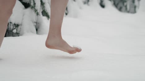 Close-up-of-caucasian-woman-walking-barefoot-in-snow.