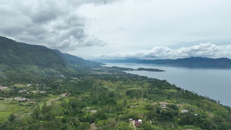 Verdant-Samosir-Island-amidst-the-expansive-Lake-Toba,-under-a-dramatic-cloudy-sky