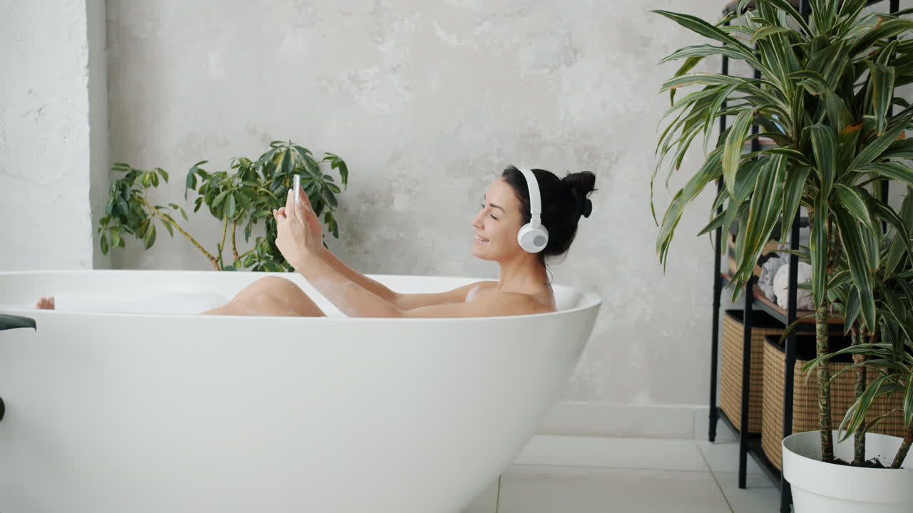 Woman Relaxing in Bathtub with Headphones and Phone