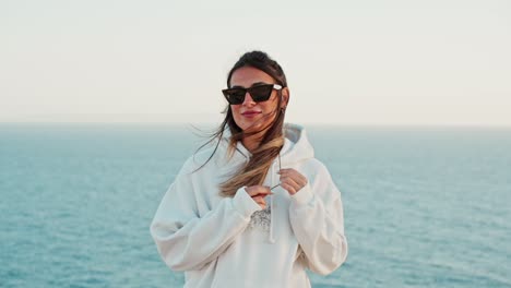 slow motion shot of a beautiful woman playing with her hair with an ocean backdrop