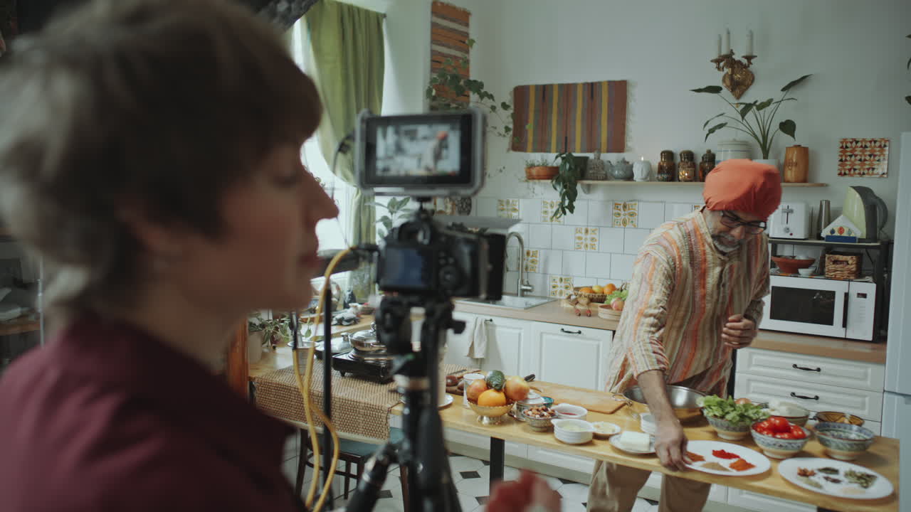 el blogger de comida indio describiendo las especias como la mujer de la cámara grabándolo