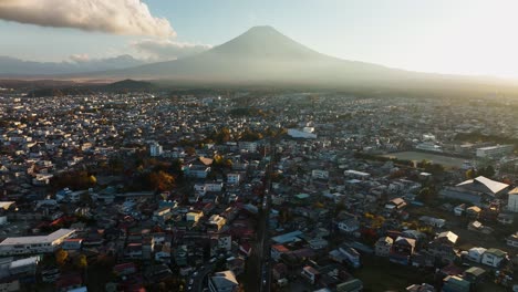 Aerial-view-tilting-over-the-Fujikawaguchiko-town,-revealing-Mt-Fuji,-sunrise-in-Japan