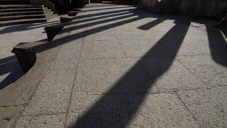 Long-shadow-cast-on-ancient-Roman-mosaic-floor-in-Dougga,-Tunisia,-under-clear-sky