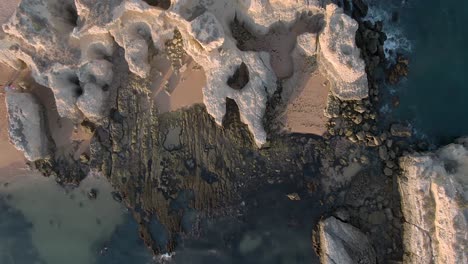 looking down view during sideways flight over waves crashing rocky beach