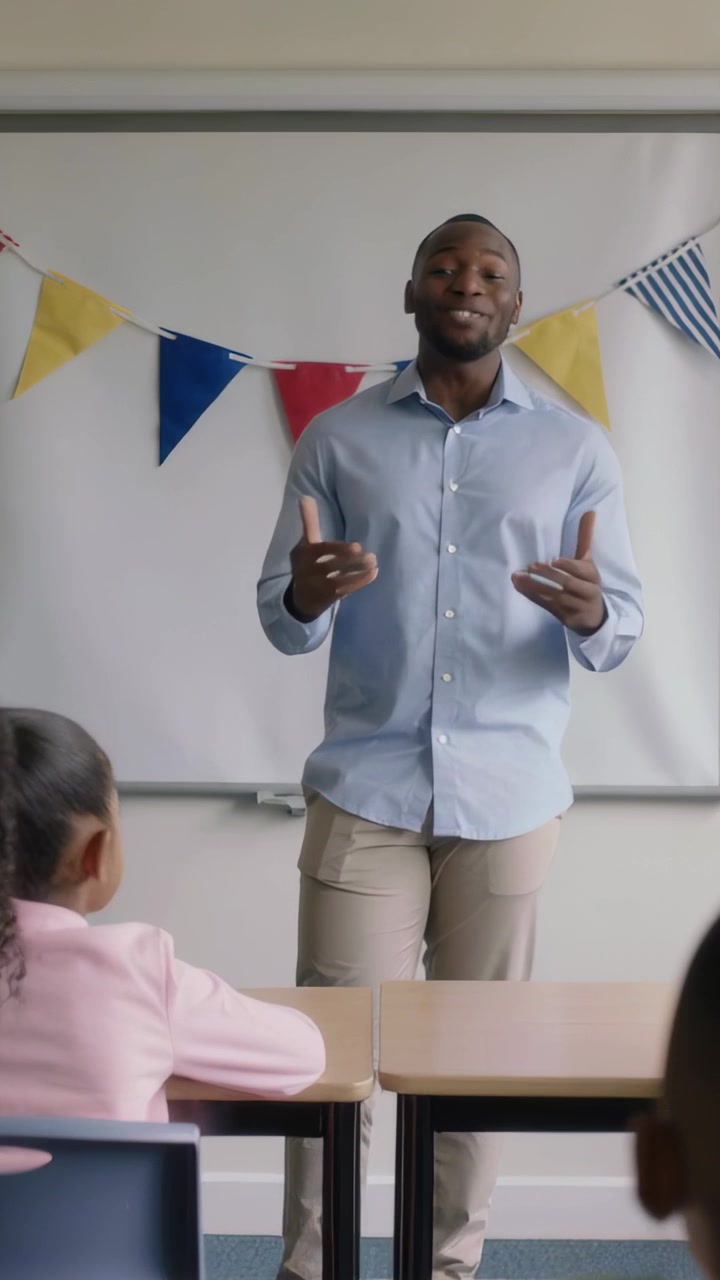 Vertical video: Starting lesson, blue-shirted teacher gesturing to engage kids, classroom bunting