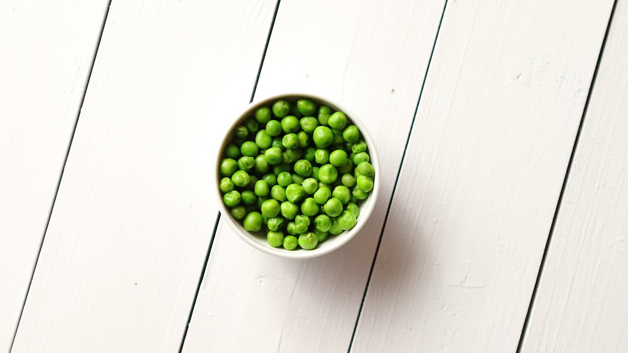 Fresh green pea seeds in a white ceramic bowl