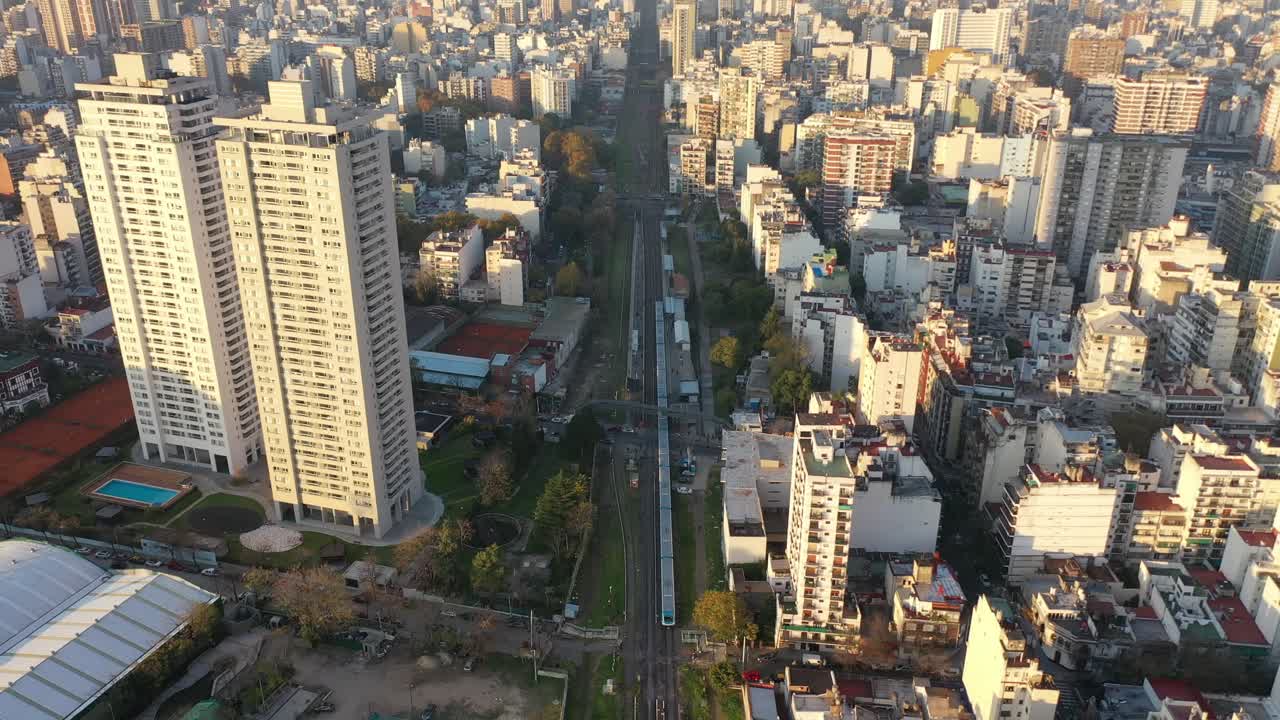 perspectiva aérea dinámica de un tren que atraviesa el corazón de la ciudad, envuelto por edificios urbanos