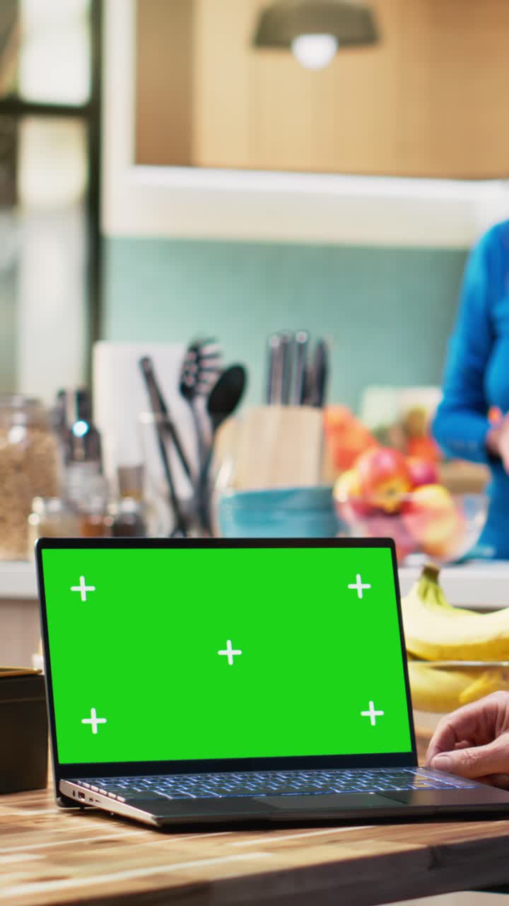 Vertical Video Chroma key laptop with retired man checking display at the table in rustic kitchen