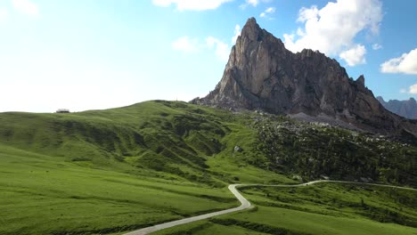 Empty-small-road-to-a-large-mountain,-blue-green-saturated-colors-at-Passo-di-Giau,-Cinque-Torri-Dolomiti-Italia