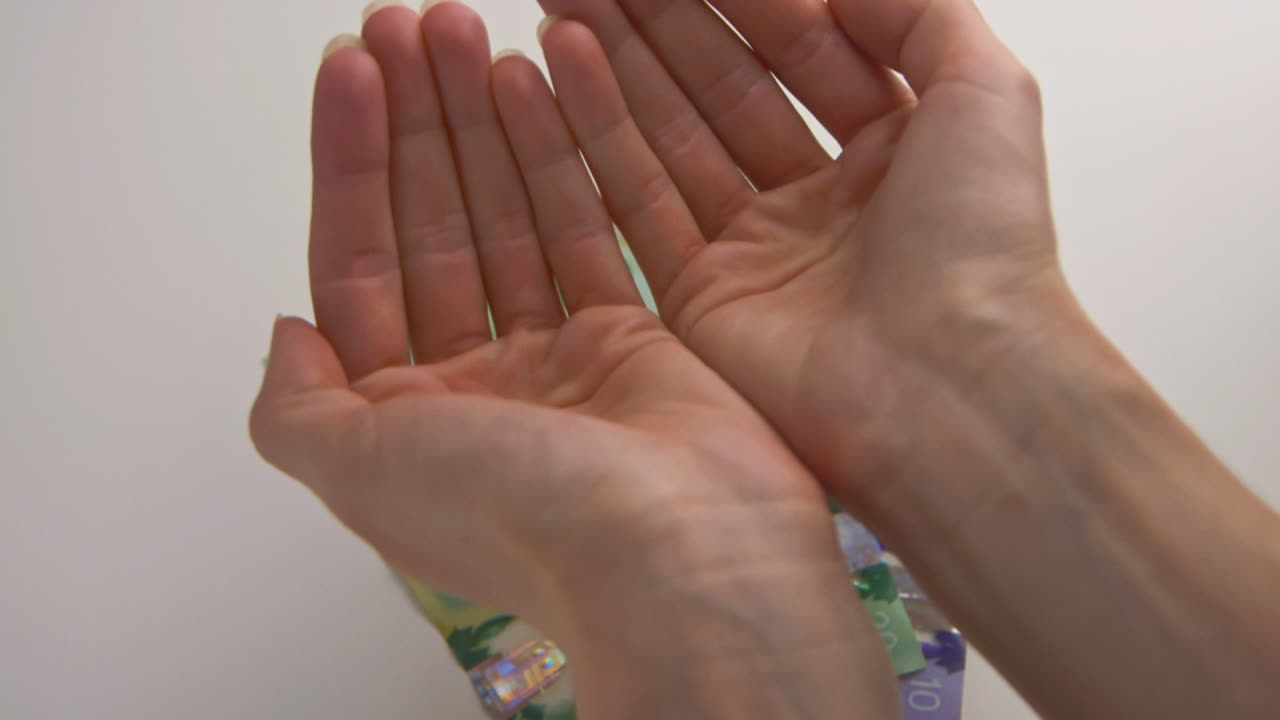 A caucasian woman's hands catching falling Canadian coins