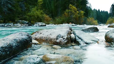 Still-shot-of-a-rocky-river-full-of-round-wet-slippery-rocks-in-crystal-clear-turquoise-water-flowing-in-the-woodlands