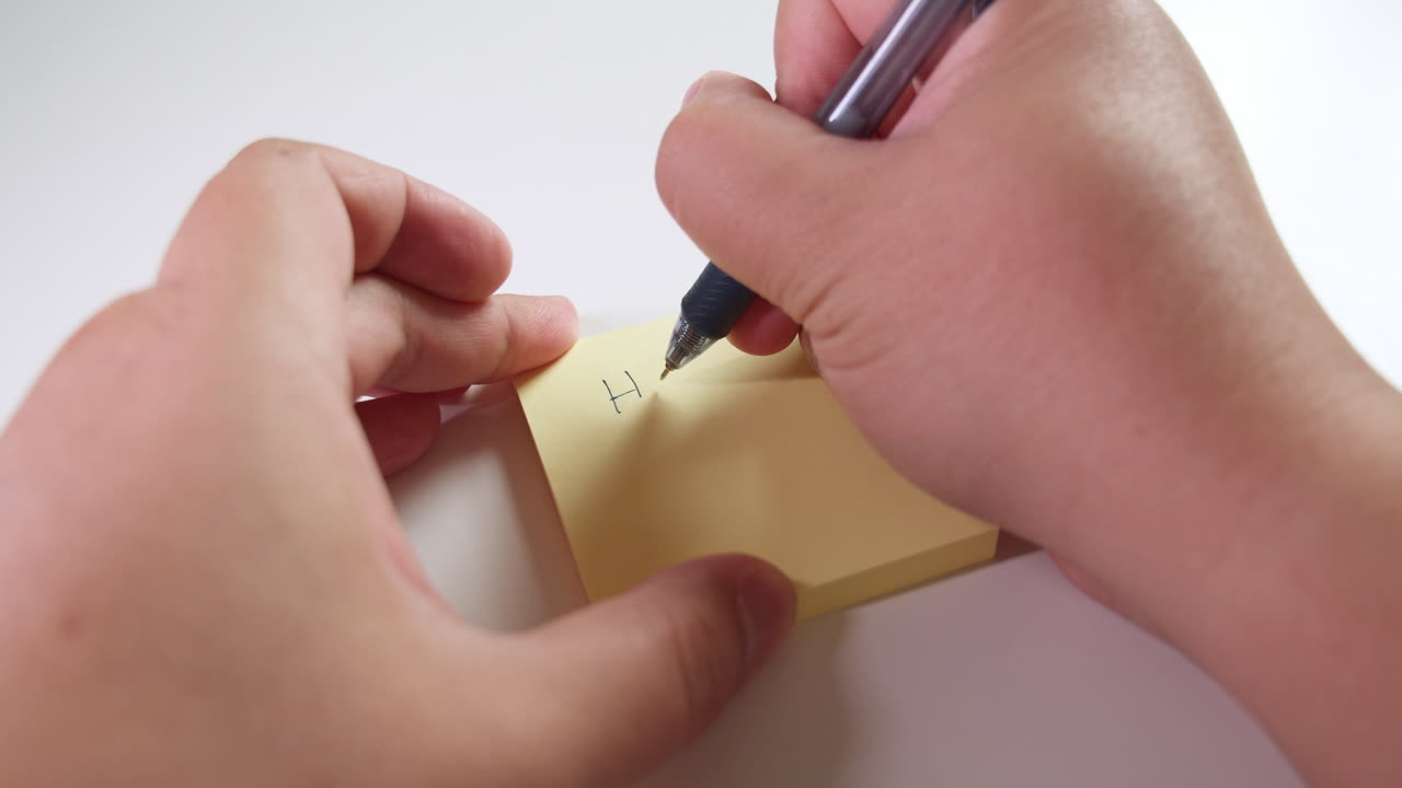 Righthand writes Happy Birthday on a &amp;quot;Post-it&amp;quot; pad while the lefthand holds it in place