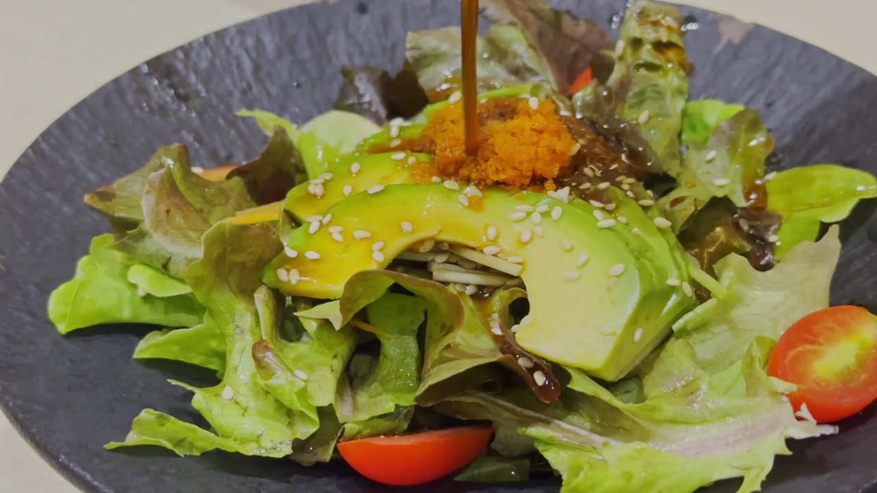 Nærbillede af en frisk avocadosalat i japansk stil, smukt anrettet med blandede grøntsager og traditionel japansk dressing. Sund og farverig salatpræsentation, der viser autentisk japansk madkultur.