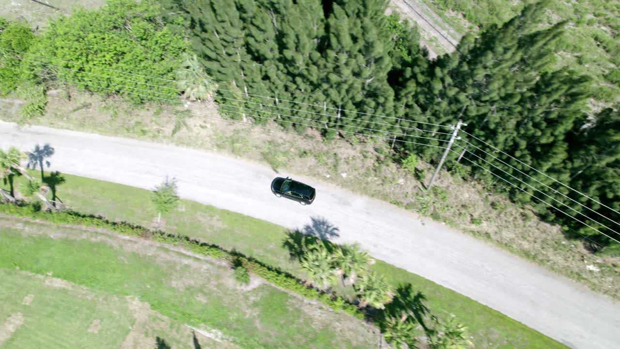 텅 빈 시골길을 달리는 검은색 자동차의 공중 촬영