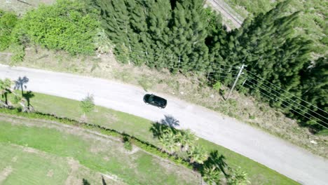 aerial shot of black car riding through empty rural road