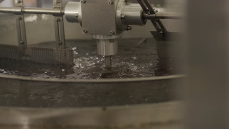 production of potato chips and snacks. industrial deep frying machine. chips are fried in a large bowl with oil. production factory line moves golden potato chips after frying.