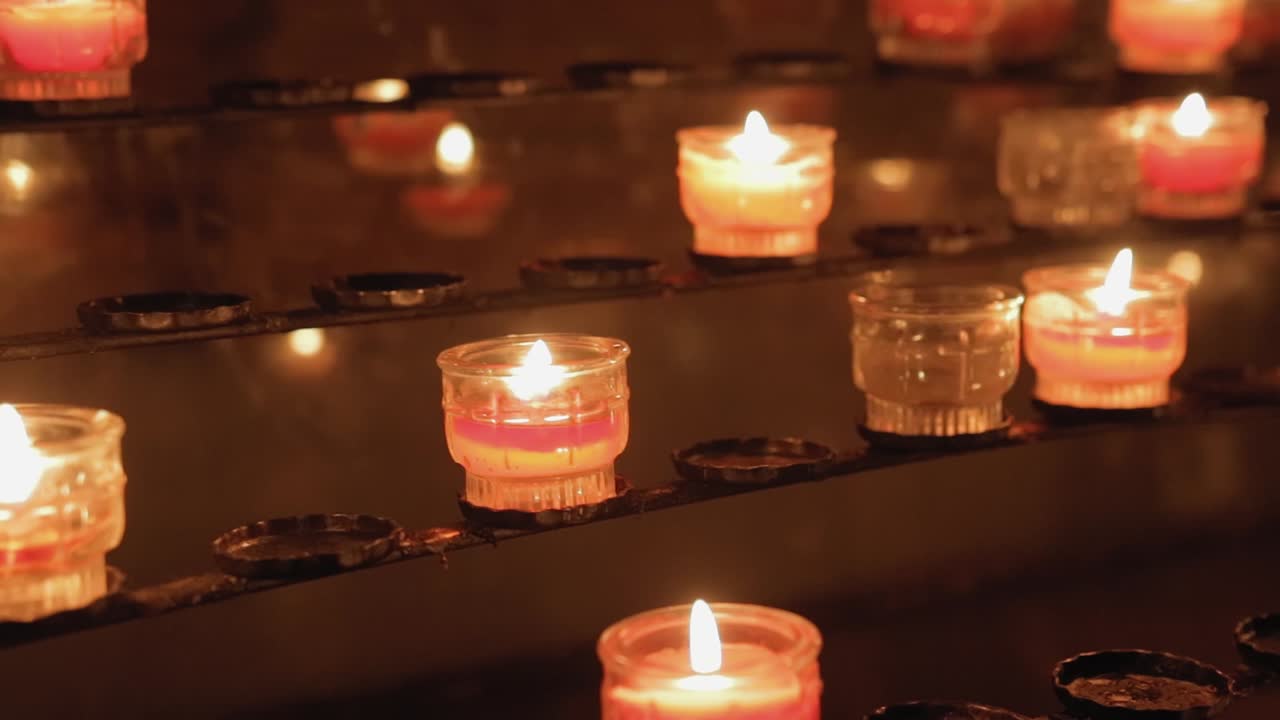 the camera moves around candles burning in the temple