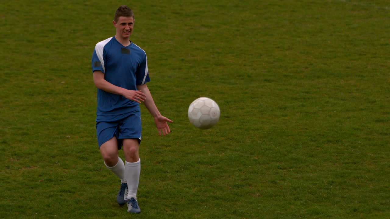 Football player in blue kicking the ball on pitch