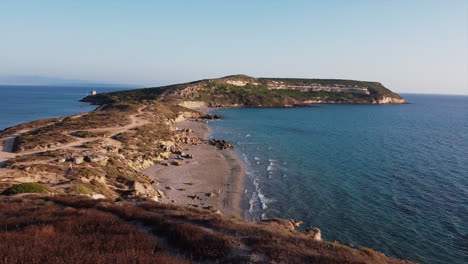 people on rocky island peninsula and sand beach in sardinia, italy