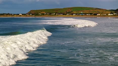 waves crash and whitewash rolls to shore as mist flies off top of water