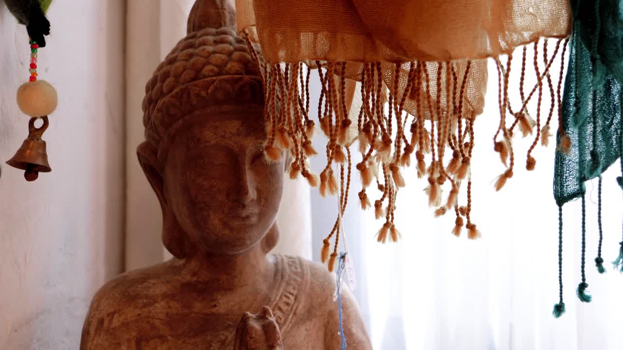un momento espiritual: mujer leyendo un libro rojo frente a la colorida estatua de buda adornada con bufanda