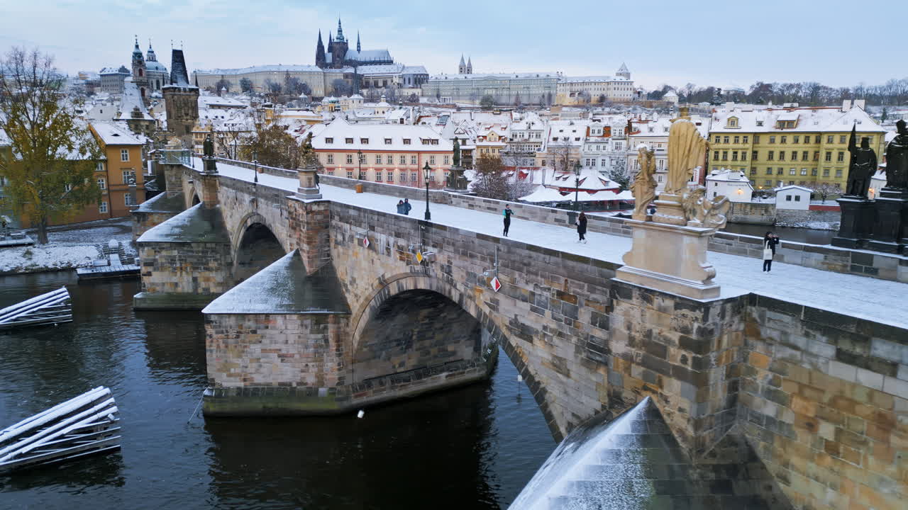 Drone aereo del medievale Ponte Carlo di pietra, innevato e illuminato dalla luce del giorno. Inverno a Praga, Repubblica Ceca