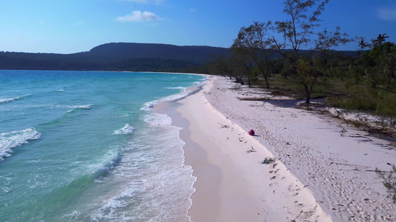 Tropical landscape showing turquoise sea washing white sand beach and green rainforest covering Koh Rong island in Cambodia. Unique aerial view flight static tripod hovering drone
