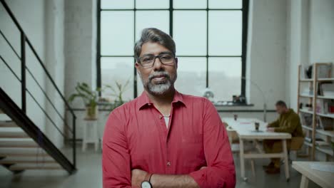 portrait of middle-aged indian businessman with arms crossed in office