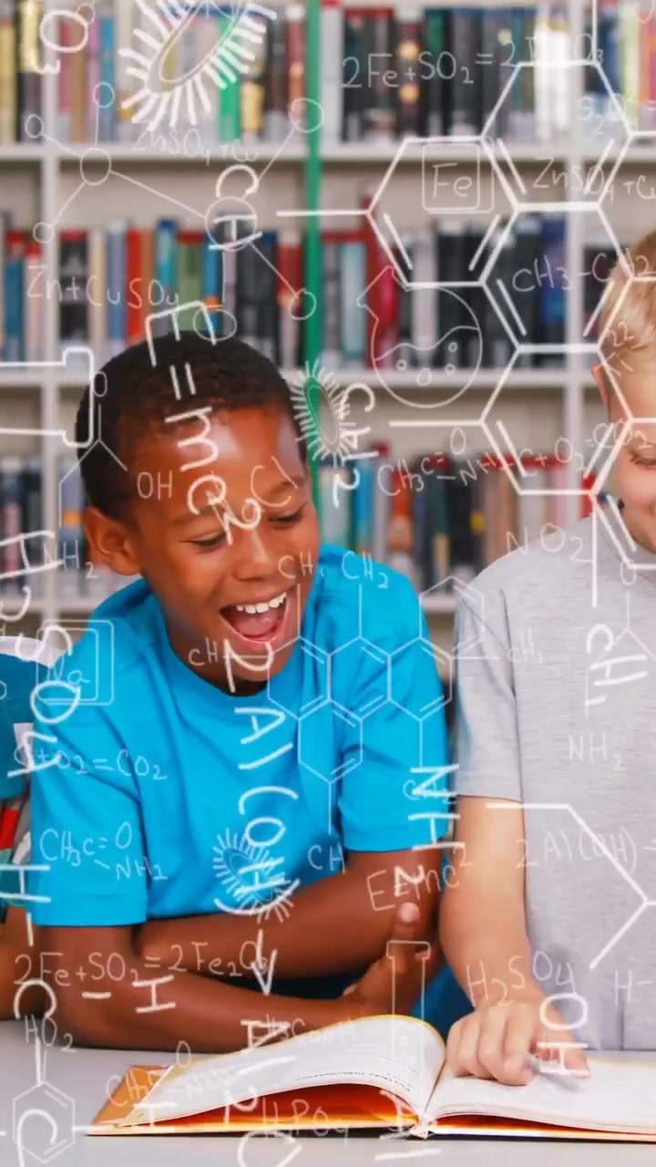 Vertical video: Two boys studying science in library, gray boy pointing, creating diagrams on book