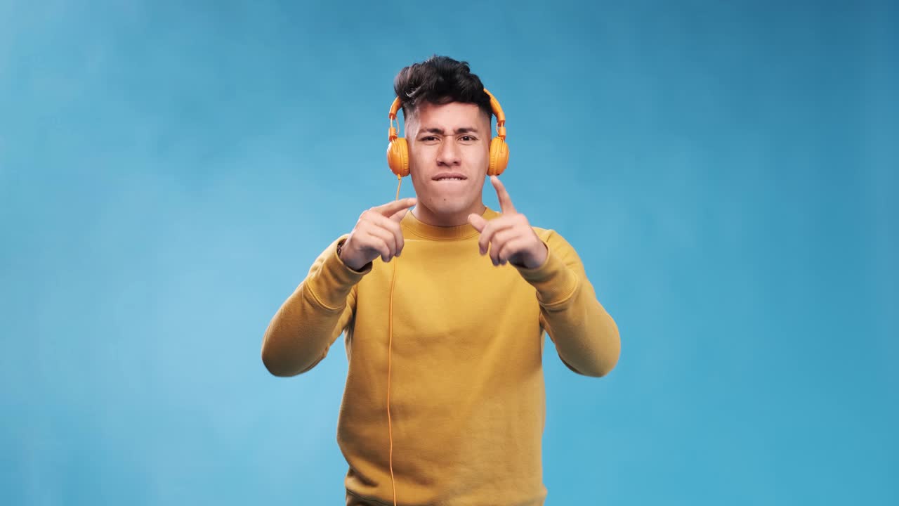 Man enjoying listening to music with headphones while standing on an isolated background.